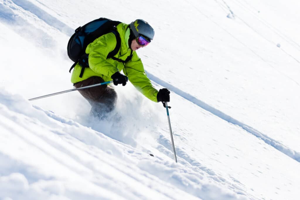 closeup-of-off-piste-skier-green-coat-skiing-through-powder