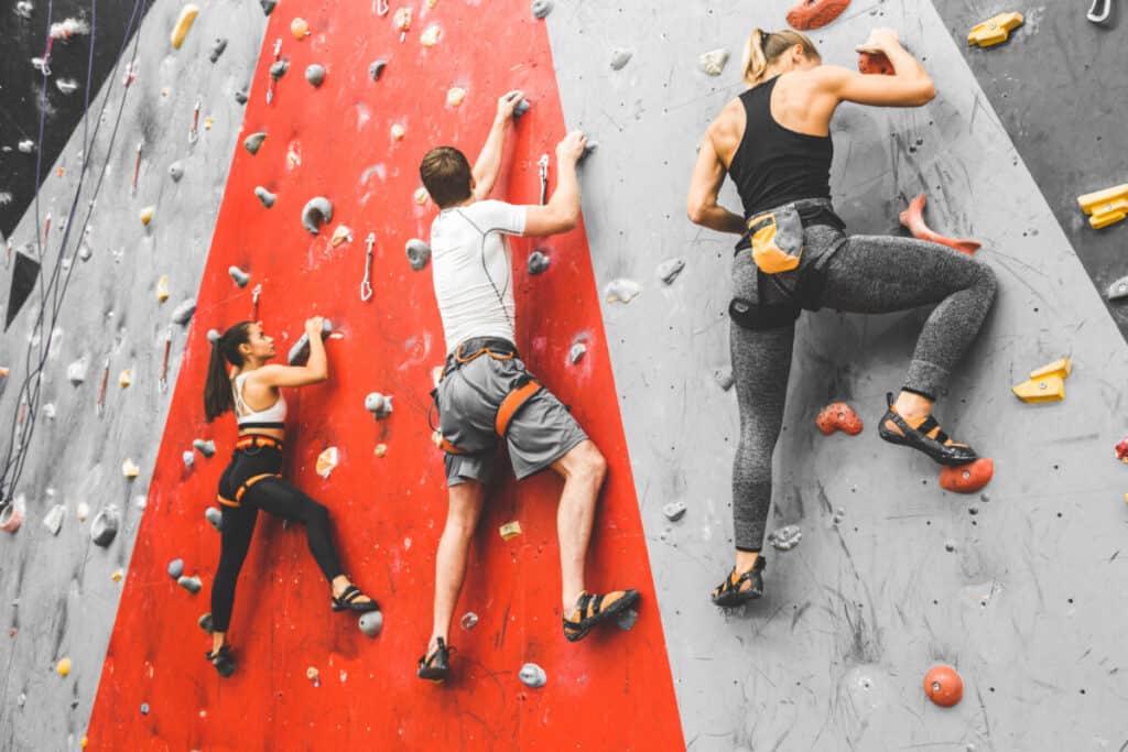 three-climbers-traversing-climbing-wall-at-indoor-climbing-facility