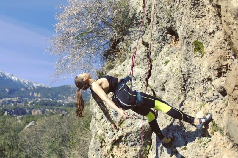 woman-laying-back-in-rock-climbing-harness-taking-a-break
