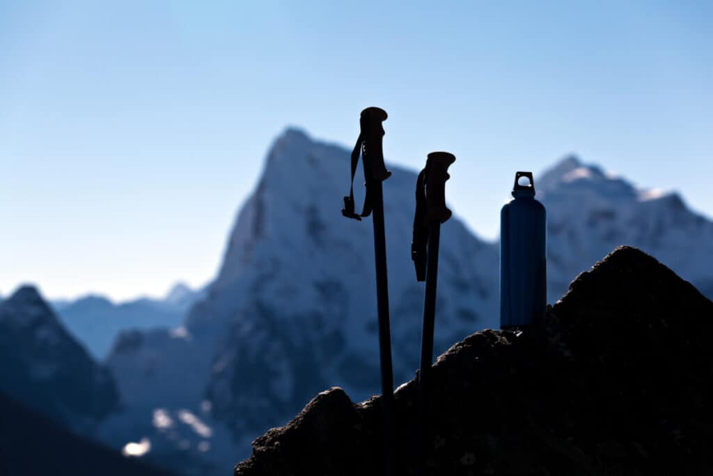 sillouette-of-insulated-thermos-and-ski-poles-mountains-in-background